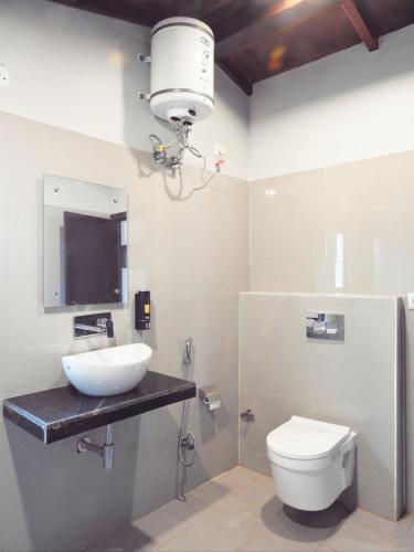 a bathroom with a sink and a toilet and a light at Entire Farm house in Jim Corbett with staff and cook in Rāmnagar