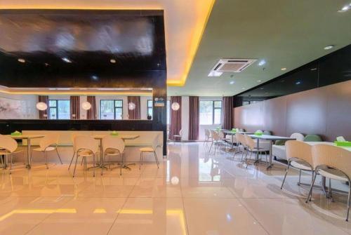 ein Restaurant mit Tischen und Stühlen und einem großen Bildschirm in der Unterkunft Jinjiang Inn Xiamen Railway Station in Xiamen