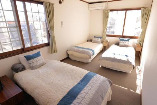 1 Schlafzimmer mit 2 Betten und Fenstern in der Unterkunft Forest and Stars Akakura Lodge in Myōkō