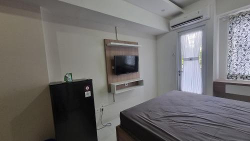 OYO 95052 Cordia Tower في Tjikuda Dua: غرفة نوم مع سرير وتلفزيون بشاشة مسطحة