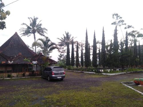 Un coche aparcado en un aparcamiento con palmeras. en OYO 95039 Hotel Agung Permata Artha, en Bojongsalam