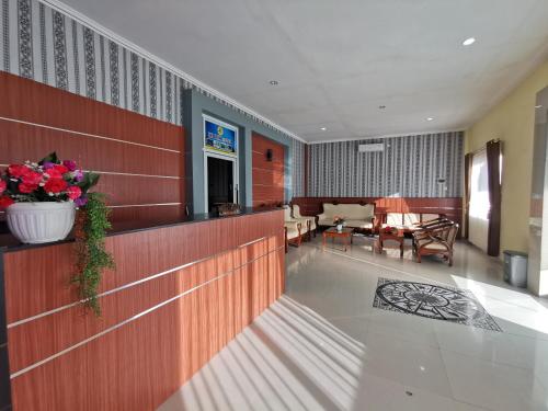 a lobby with a waiting area with a couch and flowers at OYO 95059 Ikon Guesthouse in Sengata