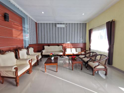 a living room with couches and a table and chairs at OYO 95059 Ikon Guesthouse in Sengata