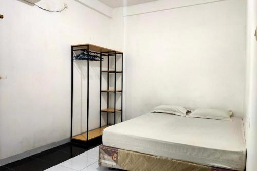 Dormitorio blanco con cama y estante en Hotel O Pondok Baruga 777 Near Sarewo Musik Studio Kendari, en Puunggolaka