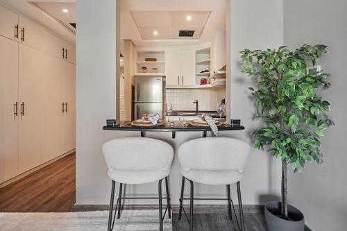 a kitchen with two white chairs and a counter at Luxury studio in Discovery Gardens near metro in Dubai