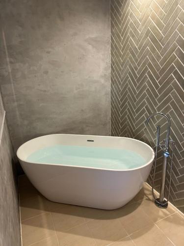a white bath tub in a bathroom with a wall at The Bath and Bed Tateyama in Toyama