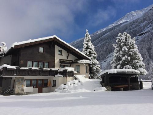 a house covered in snow in front of a mountain at Chalet Sunstar in Saas-Grund