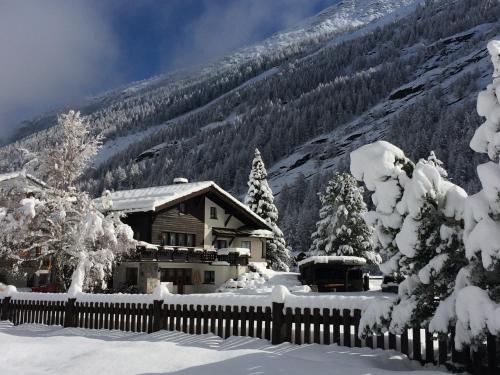 a house covered in snow in front of a mountain at Chalet Sunstar in Saas-Grund