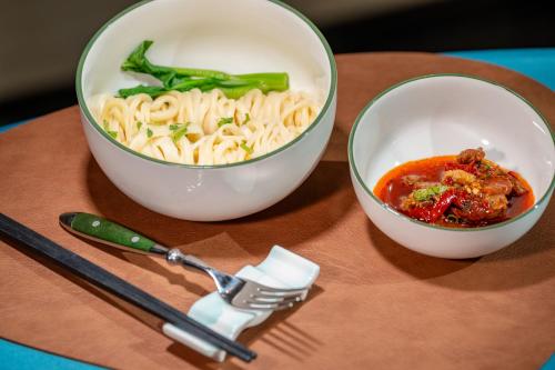 Narat新疆华美胜地那拉提英迪格酒店的两碗意大利面，一把叉子和一把刀