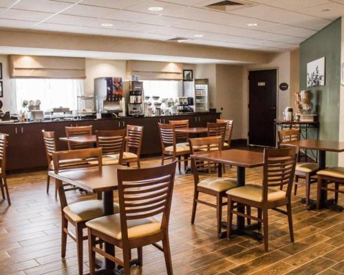 a restaurant with wooden tables and chairs and a kitchen at Sleep Inn in Geistown