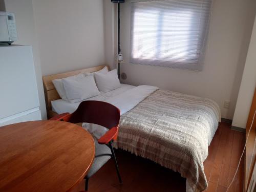 a small bedroom with a bed and a table at 大泉学園 練馬の家灯 池袋まで15分 としまえん 吉祥寺 飯能 観光に in Yagisawa