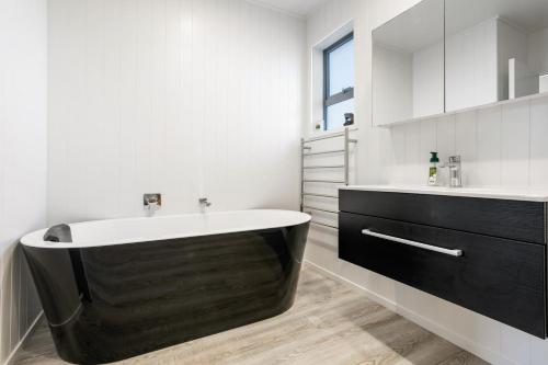 a bathroom with a black tub and a sink at Peaceful Paradise - Waihi Beach Holiday Home in Waihi Beach