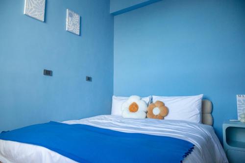 a blue bedroom with two stuffed animals on a bed at 午木wumu 民宿 in Hengchun