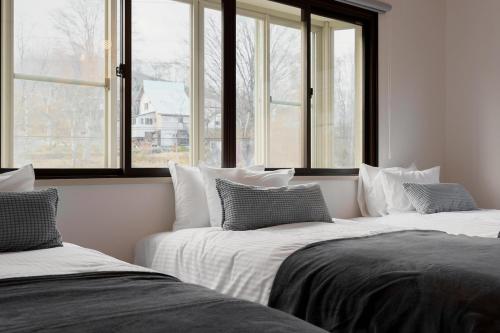 two beds in a room with two windows at Forest and Stars Akakura Sauna in Myoko