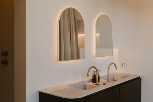 a bathroom with a sink and two mirrors at Isidore in Bruges