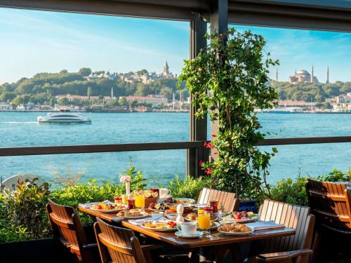 a table with food and a view of the water at Novotel Istanbul Bosphorus Hotel in Istanbul