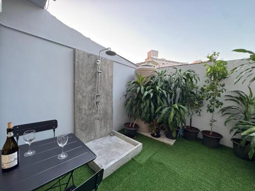 een terras met een tafel met wijnglazen en planten bij Scandi Haus near ChinaTown in Bangkok