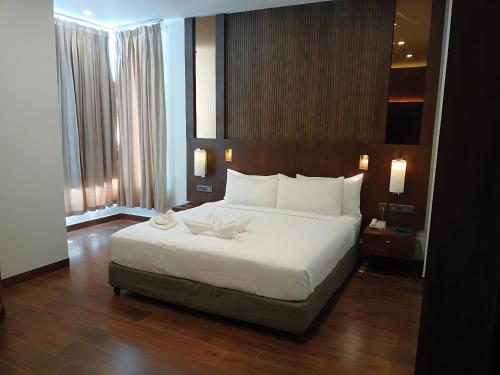 The Golden Tree Hotels Jaunpur في Jaunpur: غرفة نوم بها سرير أبيض كبير في الغرفة