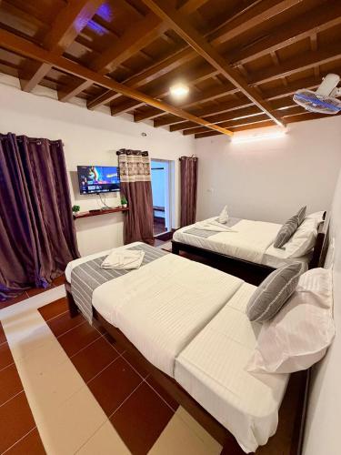 a room with two beds and a tv in it at Wildcrest Homestay in Madikeri
