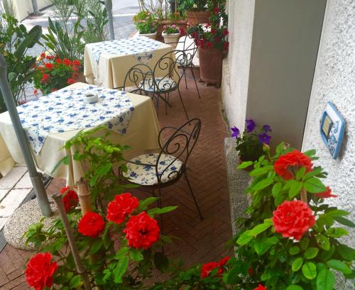 un patio con mesas, sillas y flores rojas en Donna Alda Affittacamere, en Villammare