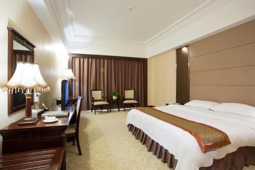 ein Hotelzimmer mit einem großen Bett und einem Schreibtisch in der Unterkunft Chaozhou Hotel in Chaozhou