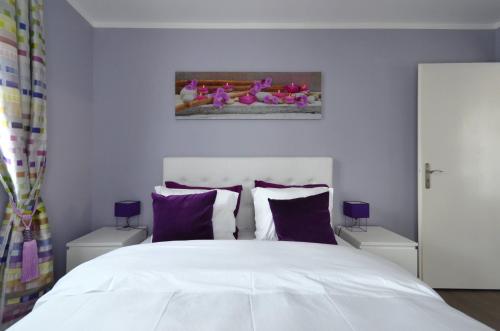 une chambre avec un grand lit blanc avec des oreillers violets dans l'établissement Djanea Luxury Apartment - Disneyland Paris, à Serris