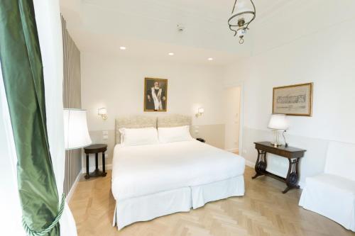 a white bedroom with a white bed and two tables at Relais Donna Lucrezia in Rome