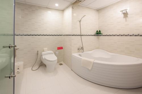 ein weißes Badezimmer mit Badewanne und Toilette in der Unterkunft White Lotus Hotel Saigon in Ho-Chi-Minh-Stadt