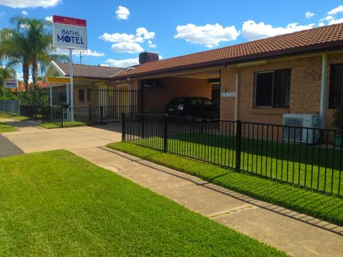 a fence in front of a house with a motel sign at Baths Motel Moree in Moree