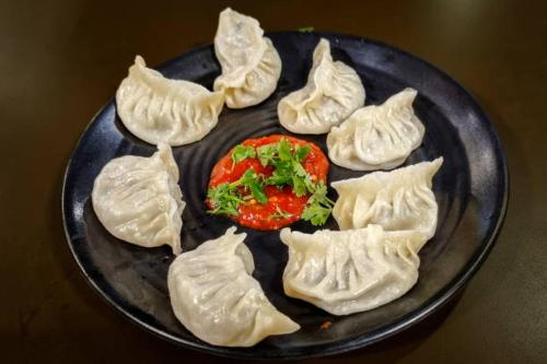 a plate of dumplings with a tomato on it at Mukhia's Homestay - Takdah in Darjeeling