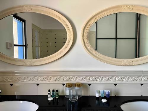zwei Spiegel an einer Wand über zwei Waschbecken im Bad in der Unterkunft The TownHouse - Neve Zedek in Tel Aviv