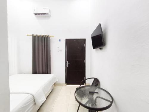 a bedroom with a bed and a table and a tv at HAJIMENA INN Syariah By Hans Management in Hajimana