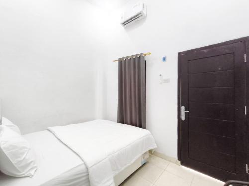 a bedroom with a bed and a black door at HAJIMENA INN Syariah By Hans Management in Hajimana