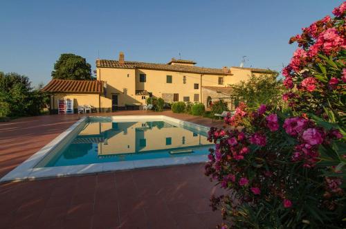 a swimming pool in front of a house with flowers at Il Torriano in Montefiridolfi