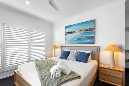 Luxury Pool Home Near Noosa & Coolum Sleeps 8 في Peregian Springs: غرفة نوم بسرير كبير مع وسائد زرقاء