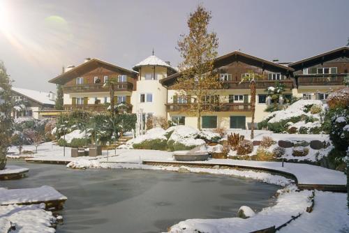 ein Gebäude im Schnee mit einem Teich davor in der Unterkunft Alpwellhotel Burggräfler in Tisens