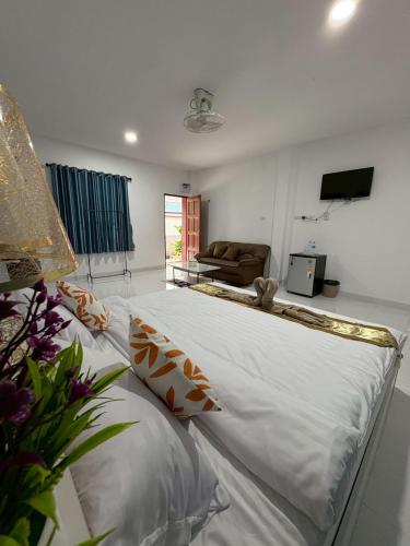 a large white bed in a living room with a couch at AN Airport Guesthouse in Nai Yang Beach