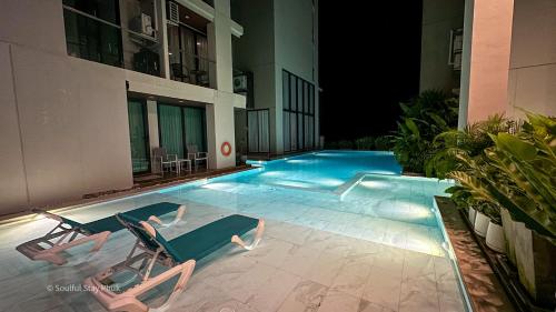 uma piscina com duas espreguiçadeiras e um edifício em Soulful Stay Phuket -Distant Seaview and Mountain View Retreat, Patong em Patong Beach