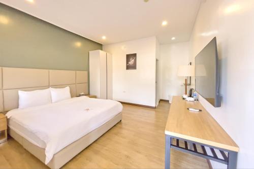クラークにあるOlle Hotel Clark City powered by Cocotelの大きな白いベッドと机のある寝室