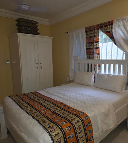 sypialnia z dużym białym łóżkiem i oknem w obiekcie Mount Pleasant w mieście Brufut