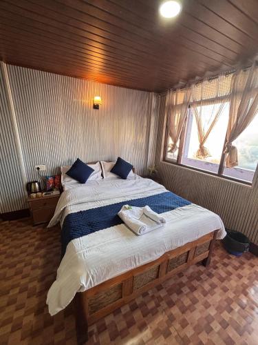 a bedroom with a large bed with two towels on it at P Square Resto Cafe n Stay in Darjeeling
