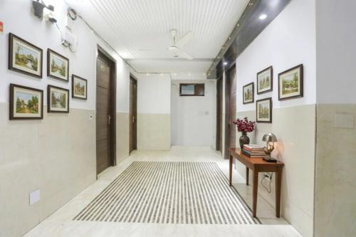 a hallway with white walls and a table and pictures on the walls at Via Lotus Palace in New Delhi