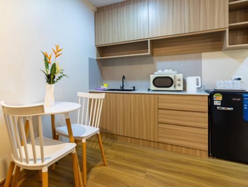 eine Küche mit einem Tisch, 2 Stühlen und einer Mikrowelle in der Unterkunft Chorbnorn Hotel in Lampang