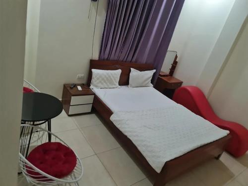 a small bedroom with a bed and a red chair at Bảo Anh Motel in Hải Dương
