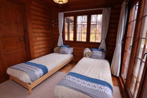 Un dormitorio con dos camas en una cabaña de madera. en green bell, en Myoko