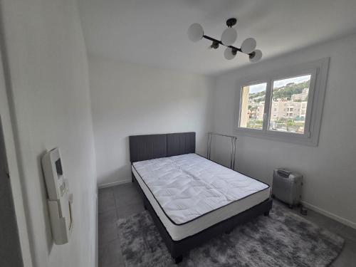ein Schlafzimmer mit einem Bett in einem Zimmer mit einem Fenster in der Unterkunft Joli 4 pièces - Terrasse vue mer - Parking - FC in Saint-Laurent-du-Var