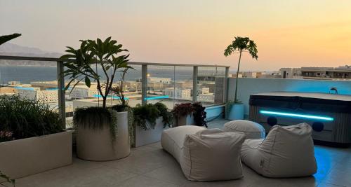 a rooftop patio with white chairs and a pool at פנטהואז אלגריה - Honeymoon Suite in Eilat