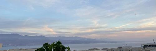 a view of a body of water with buildings and mountains at פנטהואז אלגריה - Honeymoon Suite in Eilat