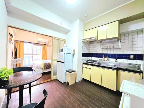 a kitchen with a table and a room with a bed at 嵐 Arashi BNB 難波西 No8112 in Osaka