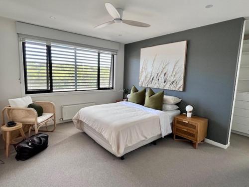 The Ebb Luxury Retreat - Just steps to the beach! في أوشن غروف: غرفة نوم بها سرير ومروحة سقف